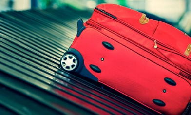 Red suitcase on airport conveyor belt at luggage reclaim